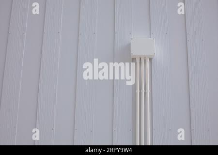 Boîte de jonction électrique en plastique blanc avec conduit installé sur le mur d'une maison en bois blanc Banque D'Images