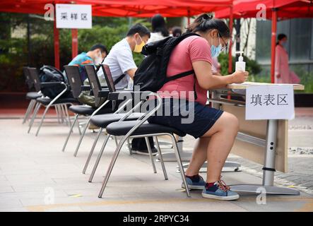 200624 -- BEIJING, le 24 juin 2020 -- les gens enregistrent des renseignements personnels avant de procéder à des tests d'acide nucléique sur un site de tests d'acide nucléique à l'hôpital universitaire de Pékin, Beijing, capitale de la Chine, le 24 juin 2020. L'hôpital universitaire de Pékin a renforcé la gestion du site de test des acides nucléiques pour éviter les risques liés au rassemblement de la foule. CHINE-PÉKIN-TEST D'ACIDE NUCLÉIQUE-GESTION CN RENXCHAO PUBLICATIONXNOTXINXCHN Banque D'Images