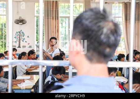 200625 -- NINGMING, le 25 juin 2020 -- Jiao Shengding regarde sa fille Jiao Lingxia enseigner à des élèves à l'école primaire d'Aidian dans le canton d'Aidian, dans le comté de Ningming, dans la région autonome de Guangxi Zhuang, dans le sud de la Chine, le 22 juin 2020. Jiao Shengding, 52 ans, est le seul enseignant du village de Zhangji, situé à la frontière entre la Chine et le Vietnam. Après avoir obtenu son diplôme de l école professionnelle secondaire du comté en 1990, Jiao a choisi d être enseignant dans sa ville natale Zhangji Village et depuis lors, il y enseigne depuis 30 ans. Au cours des trois dernières décennies, il a enseigné Mo Banque D'Images