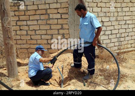 200625 -- TRIPOLI, le 25 juin 2020 Xinhua -- des ouvriers d'entretien de la compagnie libyenne d'électricité réparent une ligne dans la région de Salah al-DIN, au sud de Tripoli, en Libye, le 23 juin 2020. La plupart des villes libyennes, en particulier Tripoli, souffrent de coupures de courant quotidiennes qui durent jusqu'à 12 heures, surtout en hiver et en été. Le déficit électrique est de près de 2 500 mégawatts par jour, alors que la production actuelle ne dépasse pas 5 000 mégawatts par jour. Photo de Mohamed Arhoma/Xinhua TO GO WITH : les coupures de courant augmentent la souffrance du peuple libyen LIBYA-TRIPOLI-COUPURES DE COURANT PUBLICATIONxNOTxINxCHN Banque D'Images