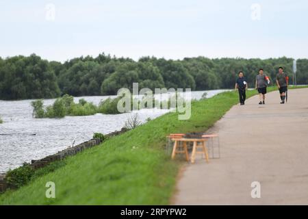 200712 -- YUEYANG, le 12 juillet 2020 -- des membres du personnel patrouillent sur une digue le long du lac Dongting dans la ville de Yueyang, province du Hunan, au centre de la Chine, le 12 juillet 2020. L eau de l une des stations hydrologiques du deuxième plus grand lac d eau douce de Chine a dépassé le niveau garanti en raison des précipitations continues et des apports en amont. Vers 3 heures du matin dimanche, l'eau à la station hydrologique de Chenglingji du lac Dongting, dans la province du Hunan, au centre de la Chine, a atteint 34,56 mètres, 0,01 mètres plus haut que le niveau garanti, et 2,06 mètres plus haut que le niveau d'alerte, selon les autorités locales. MENTON Banque D'Images