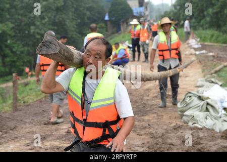 200714 -- ZONGYANG, le 14 juillet 2020 -- des villageois transportent un bois utilisé pour bloquer la tuyauterie sur le remblai d'une île fluviale dans le canton de Changsha, dans le comté de Zongyang, dans l'est de la province d'Anhui, le 14 juillet 2020. Les responsables locaux et les résidents de la municipalité de Changsha luttent contre la tuyauterie de remblai de l'île-rivière déclenchée par la montée croissante des eaux du fleuve Yangtze. Tous les résidents de l'île ont été relogés en lieu sûr. CHINA-ANHUI-ZONGYANG-FLOOD CONTROL CN HUANGXBOHAN PUBLICATIONXNOTXINXCHN Banque D'Images