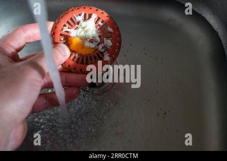 une main tenant le filtre d'évier de cuisine bouché, image de gros plan intérieure Banque D'Images