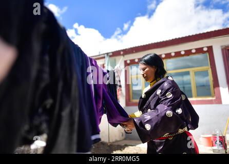 200820 -- GOLOG, 20 août 2020 -- la villageoise Degyi sèche des vêtements dans sa cour dans le village de Ghadan, dans le canton de Machali, comté de Madoi, préfecture autonome tibétaine de Golog, province du Qinghai au nord-ouest de la Chine, le 19 août 2020. En octobre 2018, un total de 1 036 résidents pauvres enregistrés ont déménagé des terres moins accueillantes du comté de Madoi à Ghadan, un village de relocalisation nouvellement construit dans la zone source du fleuve jaune. Le nouveau village dispose de meilleurs moyens de transport, ce qui permet aux villageois de trouver plus facilement du travail ou de démarrer des entreprises dans d'autres villes. Pendant ce temps, de nombreux villageois sont payés comme envir Banque D'Images