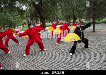 200820 -- BEIJING, 20 août 2020 -- Yang Shuqin 1st R enseigne à des personnes âgées fan de Taiji au parc du Temple du ciel à Beijing, capitale de la Chine, le 19 août 2020. Pour Zhang Liangui, 68 ans, le Temple du ciel signifie plus qu'un site du patrimoine mondial de l'UNESCO, puisqu'il fait souvent de l'exercice matinal dans le parc autour du site historique. Le 17 août, Zhang est venu tôt pour se réchauffer dans une clairière entourée de murs rouges et d'arbres verts au milieu des échos d'oiseaux et d'insectes. Coups de pied, accroupissement, jeu d'épée Taiji, un ensemble de mouvements d'échauffement ont montré son physique souple et robuste. Pendant qu'il se réchauffait, il était en attente Banque D'Images