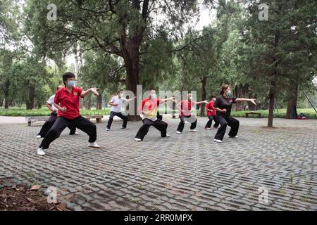 200820 -- BEIJING, 20 août 2020 -- Yang Shuqin 1st R enseigne aux personnes âgées le Baduanjin aérobie chinois traditionnel au parc du Temple du ciel à Beijing, capitale de la Chine, le 17 août 2020. Pour Zhang Liangui, 68 ans, le Temple du ciel signifie plus qu'un site du patrimoine mondial de l'UNESCO, puisqu'il fait souvent de l'exercice matinal dans le parc autour du site historique. Le 17 août, Zhang est venu tôt pour se réchauffer dans une clairière entourée de murs rouges et d'arbres verts au milieu des échos d'oiseaux et d'insectes. Coups de pied, accroupissement, jeu d'épée Taiji, un ensemble de mouvements d'échauffement ont montré son physique souple et robuste. WHI Banque D'Images