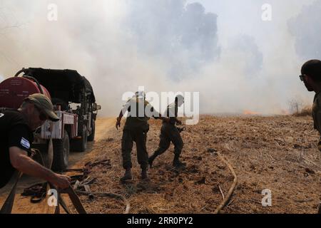 200823 -- NIR AM, 23 août 2020 -- des soldats israéliens tentent d'éteindre le feu dans une zone proche de la frontière entre Israël et la bande de Gaza, près du kibboutz du sud israélien de NIR Am, le 23 août 2020. Depuis août 6, Gaza a été témoin de tensions militaires avec l’armée israélienne, alors que les jeunes Palestiniens ont rétabli le lancement de ballons incendiaires vers les villes israéliennes adjacentes à la bande. En conséquence, des avions de combat israéliens ont ciblé des dizaines de sites militaires appartenant au mouvement Hamas, en réponse au lancement de ballons incendiaires. Photo de /Xinhua ISRAEL-NIR AM-FIRE PUBLICATION GilxCohenxMagen Banque D'Images