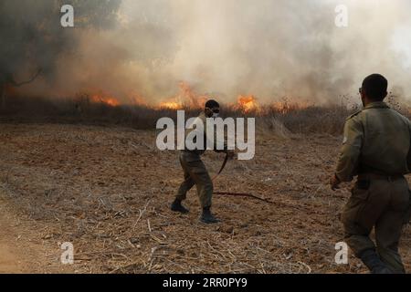 200823 -- NIR AM, 23 août 2020 -- des soldats israéliens tentent d'éteindre le feu dans une zone proche de la frontière entre Israël et la bande de Gaza, près du kibboutz du sud israélien de NIR Am, le 23 août 2020. Depuis août 6, Gaza a été témoin de tensions militaires avec l’armée israélienne, alors que les jeunes Palestiniens ont rétabli le lancement de ballons incendiaires vers les villes israéliennes adjacentes à la bande. En conséquence, des avions de combat israéliens ont ciblé des dizaines de sites militaires appartenant au mouvement Hamas, en réponse au lancement de ballons incendiaires. Photo de /Xinhua ISRAEL-NIR AM-FIRE PUBLICATION GilxCohenxMagen Banque D'Images