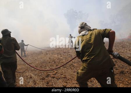 200823 -- NIR AM, 23 août 2020 -- des soldats israéliens tentent d'éteindre le feu dans une zone proche de la frontière entre Israël et la bande de Gaza, près du kibboutz du sud israélien de NIR Am, le 23 août 2020. Depuis août 6, Gaza a été témoin de tensions militaires avec l’armée israélienne, alors que les jeunes Palestiniens ont rétabli le lancement de ballons incendiaires vers les villes israéliennes adjacentes à la bande. En conséquence, des avions de combat israéliens ont ciblé des dizaines de sites militaires appartenant au mouvement Hamas, en réponse au lancement de ballons incendiaires. Photo de /Xinhua ISRAEL-NIR AM-FIRE PUBLICATION GilxCohenxMagen Banque D'Images