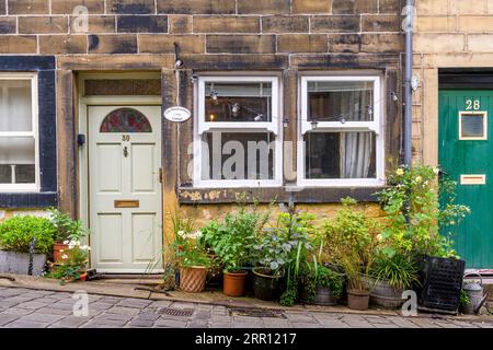 Le joli village de Haworth, près de Keighley dans les Pennines, West Yorkshire. Cette route escarpée emblématique est main Street, bordée de jolis chalets. Banque D'Images