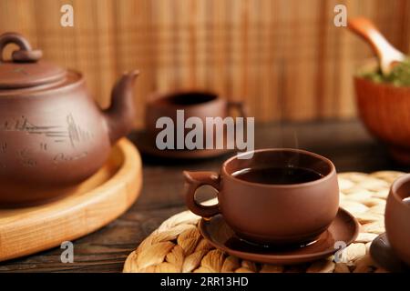 Cérémonie du thé. Ustensile traditionnel de thé asiatique, servant un set authentique. Personne versant du thé de la théière de la poterie brune à la théière. Plateau en bambou. Style de vie. Nous Banque D'Images