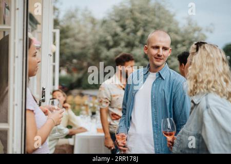 Amis masculins et féminins appréciant le vin pendant le dîner au café Banque D'Images