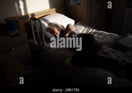 Femme âgée endormie sur son lit de maison de soins, Angleterre, Royaume-Uni Banque D'Images