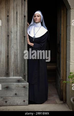 Jeune femme adulte vêtue d'habits authentiques et du voile d'une religieuse catholique dans une chapelle médiévale Banque D'Images