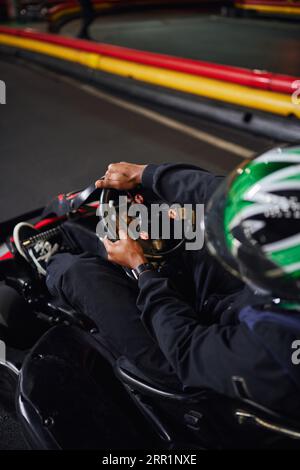 go cart speed drive, pilote afro-américain en casque tenant le volant de la voiture de course de karting Banque D'Images