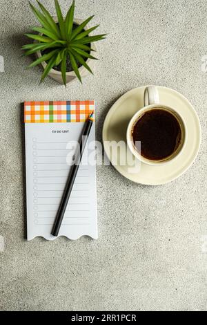 Vue de dessus de la tasse de café près de la plante en pot et note avec un crayon placé sur la table grise Banque D'Images