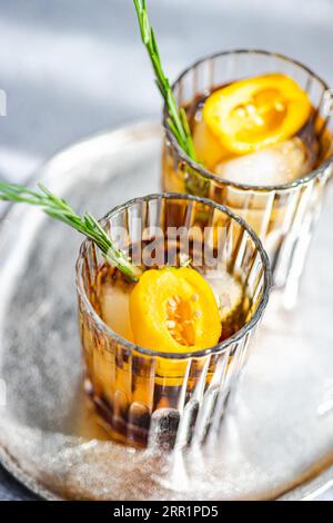 Angle élevé de cocktails Margarita épicés servis avec des glaçons et des tranches de fruits frais placés sur un plateau sur fond gris Banque D'Images