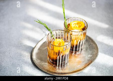 Angle élevé de cocktails Margarita épicés servis avec des glaçons et des tranches de fruits frais placés sur un plateau sur fond gris Banque D'Images