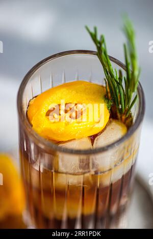 Angle élevé de cocktail Margarita épicé servi avec des glaçons et des tranches de fruits frais placés sur un plateau sur fond gris Banque D'Images