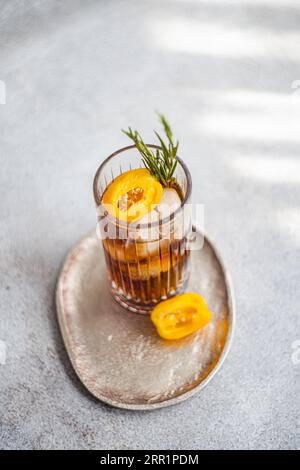 Angle élevé de cocktail Margarita épicé servi avec des glaçons et des tranches de fruits frais placés sur un plateau sur fond gris Banque D'Images