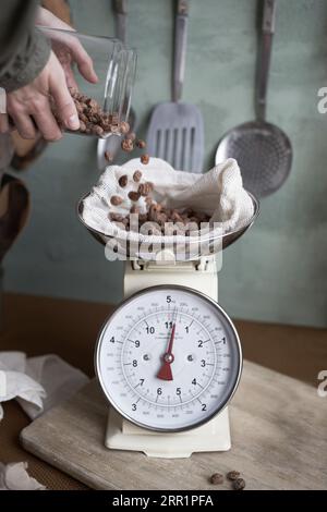 Vue de côté de la récolte anonyme femelle utilisant une échelle pour mesurer le poids des amandes tout en faisant la boisson horchata dans la cuisine Banque D'Images