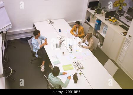 Vue de la caméra montée au-dessus des collègues de l'équipe multiraciale se regardant les uns les autres assis à la table de réunion du conseil et discutant du projet Banque D'Images