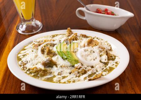 Délicieuse salade Pico de Gallo dans un bol chilaquiles avec des oignons d'avocat tortillas de maïs servis sur une assiette blanche avec du fromage cru sur une surface en bois Banque D'Images