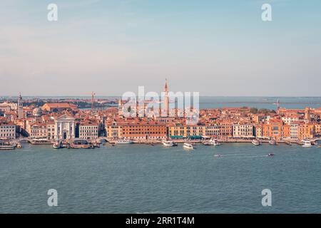 Vue aérienne pittoresque du paysage urbain avec des bateaux naviguant sur le canal et le Campanile historique de St Marc et les bâtiments au toit rouge contre le ciel nuageux à Venise Banque D'Images