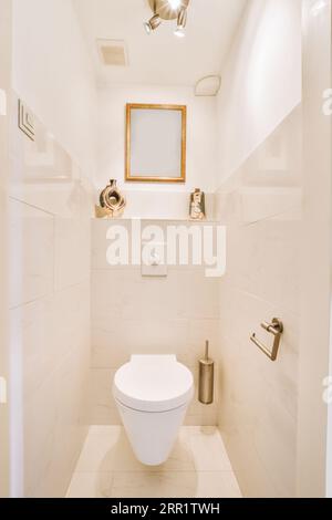 Intérieur des toilettes étroites avec toilettes suspendues avec murs blancs et sol en damier Banque D'Images