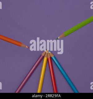 Crayons en bois de différentes couleurs sur fond violet. Composition d'art minimaliste. Banque D'Images