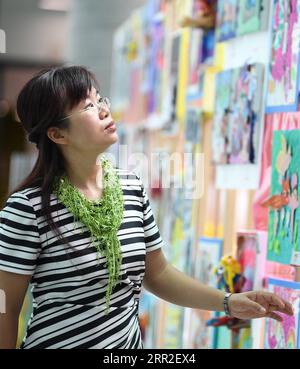 201010 -- SHENZHEN, le 10 octobre 2020 -- Xiong Yonglan regarde des peintures pour enfants au palais des jeunes du district de Bao an à Shenzhen, dans la province du Guangdong du sud de la Chine, le 8 septembre 2020. Xiong Yonglan, qui est maintenant gestionnaire au palais des jeunes du district de Bao an à Shenzhen, s'efforce d'améliorer la vie dans la ville depuis le moment où elle est entrée dans la ville. En 1992, Xiong Yonglan, âgé de 18 ans, est arrivé à la succursale de Shenzhen de Mabuchi Motor et a travaillé sur la chaîne de montage. Bientôt, avec ses performances exceptionnelles sur le terrain, Xiong est devenue inspectrice qualité à plein temps. Dans ses temps libres, elle étudia Banque D'Images