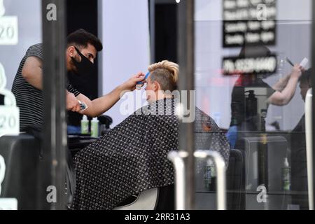 201019 -- SYDNEY, le 19 octobre 2020 -- Un coiffeur portant un masque facial sert un client dans le quartier central des affaires de Melbourne, Victoria, Australie, le 19 octobre 2020. À la suite de ces changements, le Premier ministre australien Scott Morrison a publié une déclaration conjointe avec d’autres ministres de haut rang saluant l’assouplissement partiel, mais ajoutant que l’État devrait aller plus loin pour alléger le fardeau des entreprises et des particuliers en difficulté. POUR ALLER AVEC Spotlight : la pression reste sur le confinement de l’État australien malgré un assouplissement partiel photo par /Xinhua AUSTRALIA-COVID-19-LOCKDOWN-EASE BaixXue PUBLICATIONxNOTxINxCHN Banque D'Images