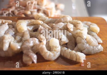 Crevettes fraîches sur une planche de bois avec lumière naturelle, concept de cuisine maison Sinples. Banque D'Images