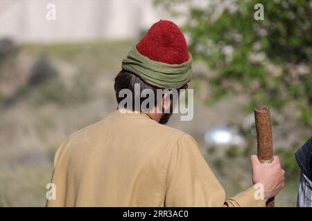 Un jeune turc en vêtements traditionnels. Vue arrière d'un jeune homme marchant dans la nature. Banque D'Images