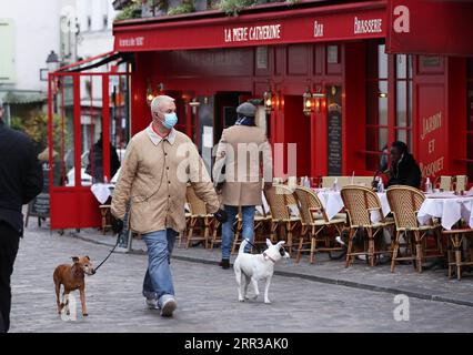 201029 -- PARIS, le 29 octobre 2020 -- Un homme promène ses chiens sur la place du Tertre à Montmartre, Paris, France, le 28 octobre 2020. La France entrera en confinement national à partir de vendredi pour endiguer la deuxième vague de l’épidémie de coronavirus, a annoncé mercredi soir le président Emmanuel Macron. La France a enregistré mercredi 36 437 nouvelles infections à COVID-19, 3 020 de plus que le nombre enregistré au cours des 24 heures précédentes. Le nombre cumulé de cas de coronavirus a grimpé à 1 235 132, dont 35 785 décès, en hausse de 244 en une journée, ont montré les chiffres publiés par l’Agence de la santé publique. FRANCE-PARIS-ÉCLUSE Banque D'Images