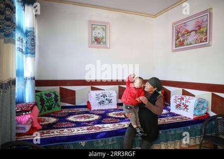 201110 -- DONGXIANG, le 10 novembre 2020 -- Une villageoise joue avec son petit-enfant dans le village de Bulenggou, dans le comté autonome de Dongxiang de la préfecture autonome de Linxia hui, dans la province du Gansu, au nord-ouest de la Chine, le 9 novembre 2020. Le village de Bulenggou était autrefois une zone gravement appauvrie. Depuis le début des travaux de lutte contre la pauvreté, le village a changé avec de meilleures infrastructures, ce qui permet aux villageois d’accéder à l’eau potable, aux routes, au centre de santé et à une école primaire bien équipée. L'élevage de bétail est devenu la principale industrie du village de Bulenggou, où les villageois ont vu leur revenu inc Banque D'Images