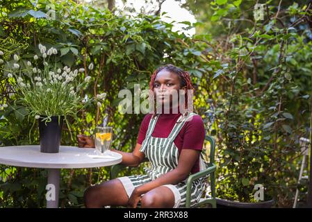 Portrait d'une personne noire non binaire assise dans un café en plein air Banque D'Images