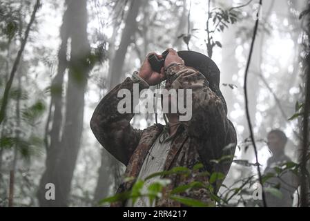 201117 -- HAIKOU, le 17 novembre 2020 -- Un géomètre du gibbon observe avec des jumelles dans les forêts tropicales humides de la montagne Bawangling dans la province de Hainan du sud de la Chine, le 16 novembre 2020. Connus comme les primates les plus rares au monde, les gibbons de Hainan sont de plus en plus nombreux grâce à un environnement amélioré. Les données les plus récentes du ministère des forêts de la province suggèrent qu il y a 33 gibbons vivant dans cinq familles, une augmentation de la population par trois depuis les années 1970 Les singes à crête noire ne peuvent être trouvés que dans la réserve naturelle nationale de Bawangling sur l'île de Hainan. Ils vivent dans des arbres de forêt tropicale de plus de 10 mètres de haut et Banque D'Images