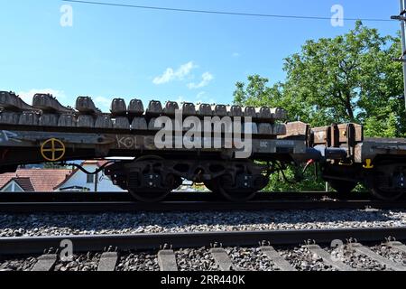 Un wagon de chemin de fer chargé de traverses en béton se dresse sur les rails menant à la gare d’Urdorf en Suisse. Banque D'Images