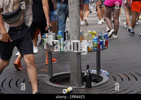 Bouteilles vides et déchets alimentaires mis sur la protection métallique de l'arbre dans la rue. Banque D'Images