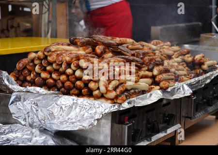 Saucisses blanches rôties empilées et placées sur un radiateur électrique afin de les garder au chaud. Ils sont exposés sur un comptoir prêt à la vente. Banque D'Images