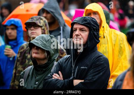 Un couple dans Wets dans l'arène principale Mountain Stage dans la pluie et la boue de pluie de tempête. Green Man Festival, Brecon, pays de Galles, Royaume-Uni, 2023. Photo : Rob Watkins Banque D'Images