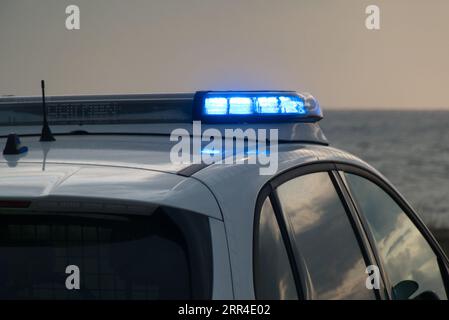 Voiture de police sur la plage de la mer du Nord avec les lumières allumées Banque D'Images