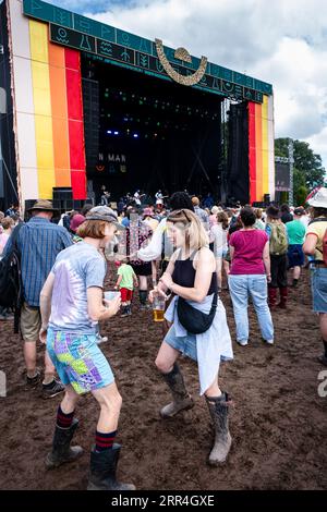 Un jeune couple dansant avec des bières dans la boue à la Mountain Stage au Green Man Festival, Brecon, pays de Galles, Royaume-Uni, 2023. Photo : Rob Watkins Banque D'Images