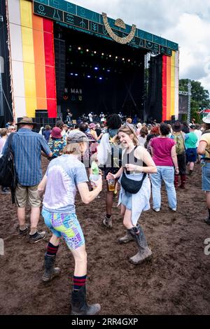 Un jeune couple dansant avec des bières dans la boue à la Mountain Stage au Green Man Festival, Brecon, pays de Galles, Royaume-Uni, 2023. Photo : Rob Watkins Banque D'Images