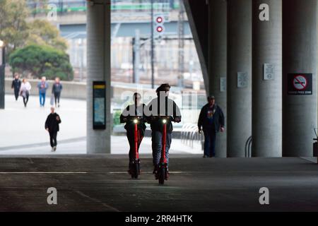 Les conducteurs de scooter électrique en ville font la navette et voyagent sur des voies partagées à Melbourne, en Australie. Banque D'Images