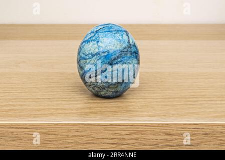 Une boule en pierre synthétique bleue et noire sur une table en bois de chêne Banque D'Images