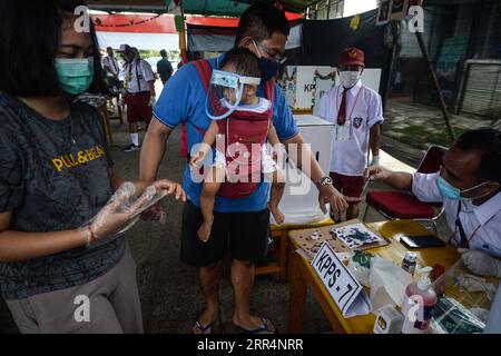 201210 -- SOUTH TANGERANG, le 10 décembre 2020 -- un fonctionnaire donne de l'encre comme marque à un homme portant un masque facial après avoir voté dans un bureau de vote lors de l'élection du directeur régional de 2020 à South Tangerang, Indonésie, le 9 décembre 2020. INDONÉSIE-ÉLECTION RÉGIONALE-COVID-19 AGUNGXKUNCAHYAXB. PUBLICATIONxNOTxINxCHN Banque D'Images