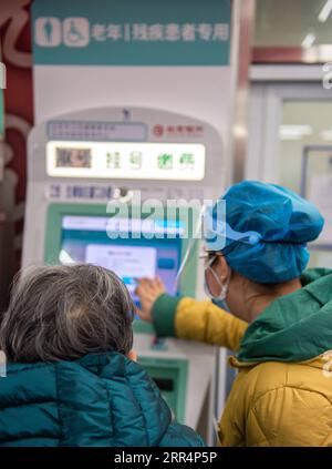 201210 -- BEIJING, le 10 décembre 2020 -- un membre du personnel aide une personne âgée à prendre le reçu de rendez-vous à partir d'une machine dédiée aux personnes âgées et aux handicapés à l'hôpital Xuanwu de l'Université médicale de la capitale à Beijing, capitale de la Chine, le 10 décembre 2020. La Chine a lancé une campagne de trois ans pour aider les seniors du pays à franchir la fracture numérique et à profiter du développement de la technologie intelligente. Le gouvernement a récemment publié un plan spécifiant des mesures pour aider les personnes âgées à surmonter les obstacles à l'utilisation des technologies intelligentes tout en maintenant les services traditionnels pour elles. Le plan est Banque D'Images