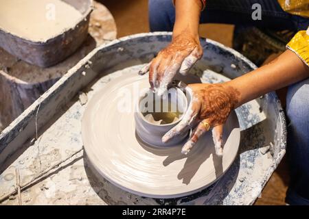 Une femme apprenant la poterie en utilisant de l'argile sur la roue de potier Banque D'Images